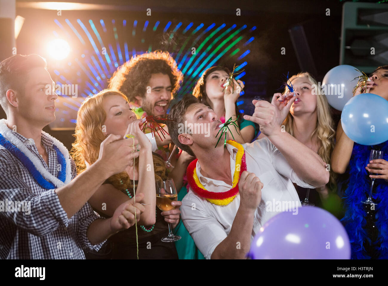 group-of-friends-blowing-party-horn-in-bar-H3TRJN.jpg